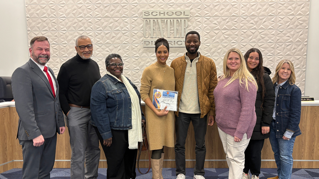 Ms. Gabrielle Young, her family, and members of the Red Bridge Elementary team pose with Superintendent Dr. Troy Hogg and Board Chair Marcie Calvin.