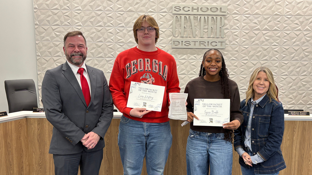Superintendent Troy Hogg, CHS student Lucas Westring, CHS student Icysis Buckle, and Board Chair Marcie Calvin smile in front of the board dias.