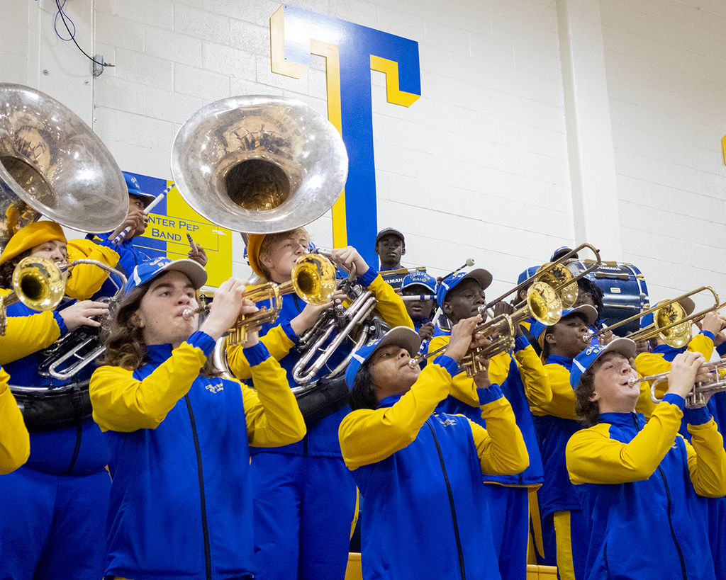 CHS horn section stands in the gym, playing at a basketball game.