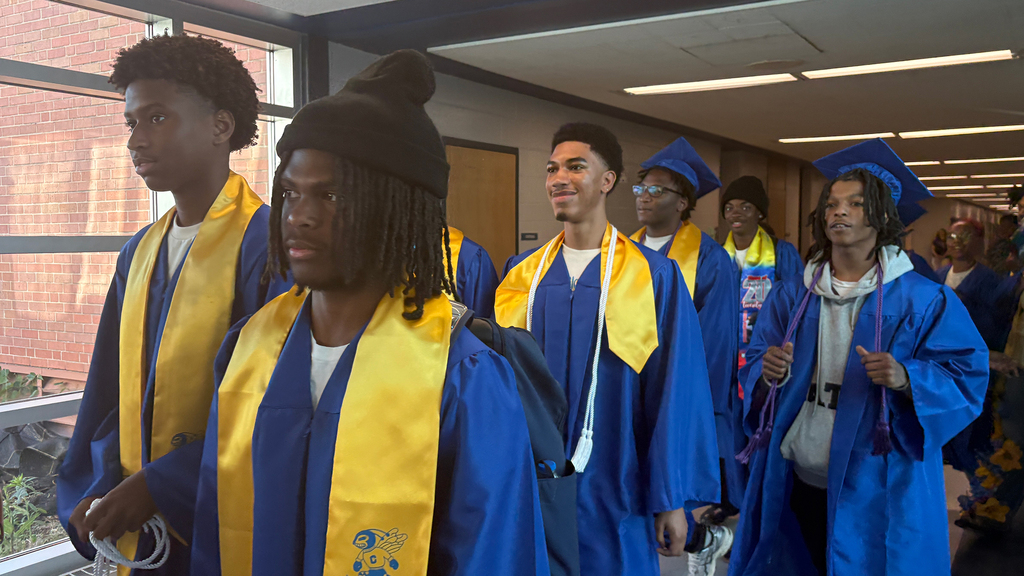 Seniors walk down the CHS hall with their blue graduation caps and gowns.
