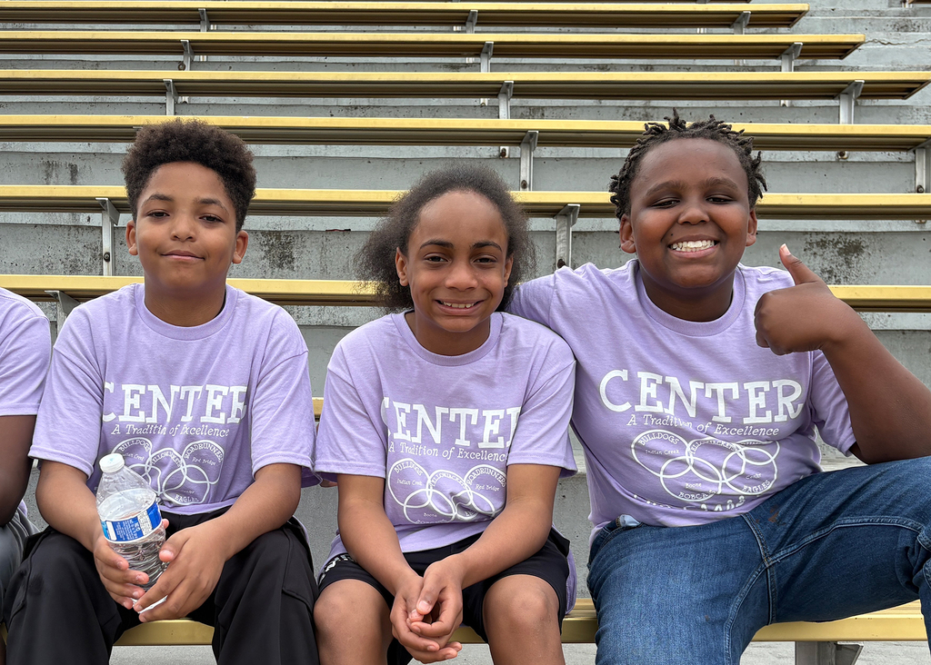 Three students sit in the CHS football stands at Junior Olympics.