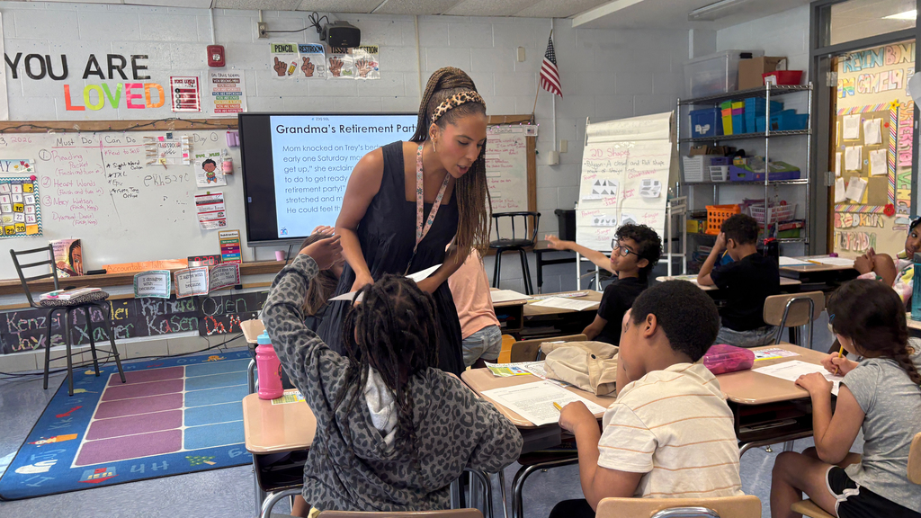 Ms. Gabrielle Young stands in front of her classroom, in front of a row of students at their desks.