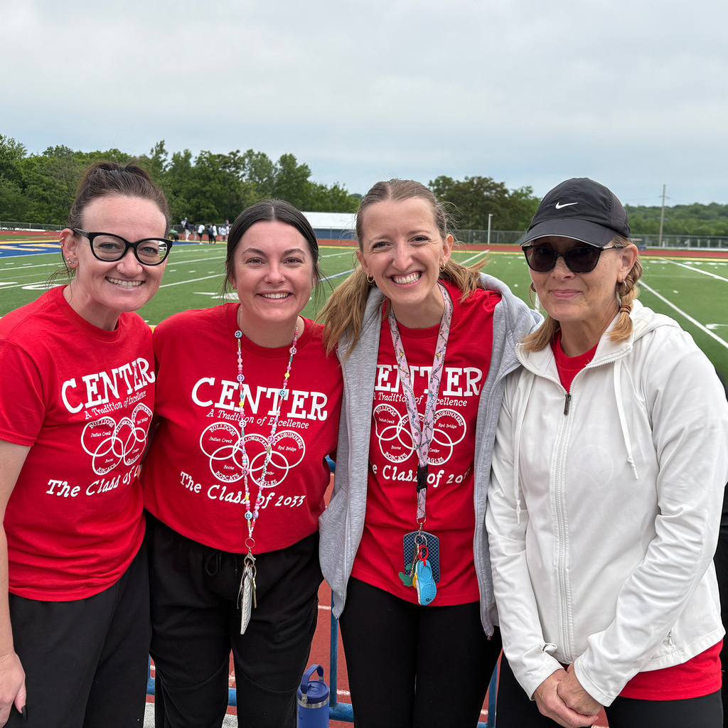 Four Center School District employees stand together with the CHS football field in the background.