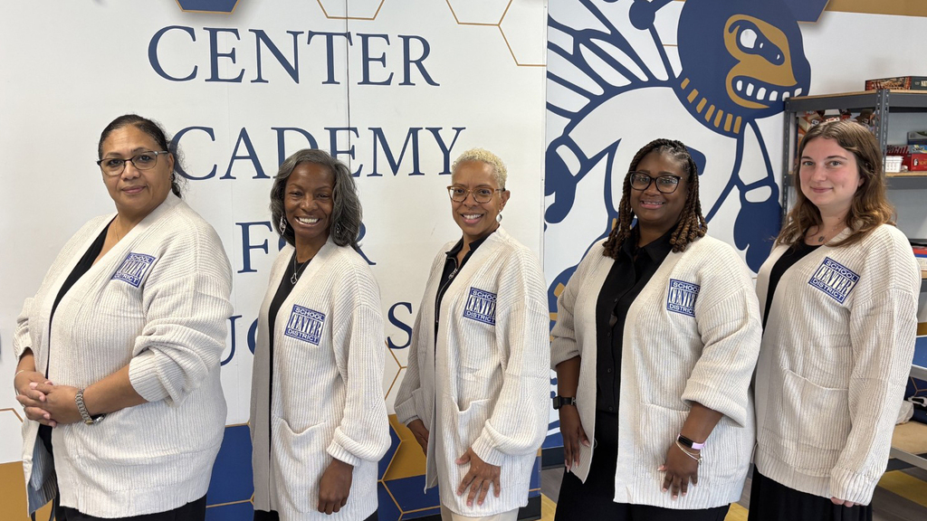 Center School District Human Resources team stands in a row in matching cardigans.