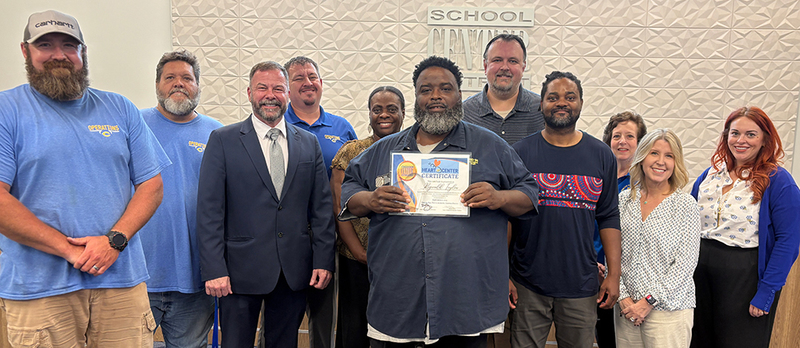 Group of smiling staff members stands in front of the board podium.
