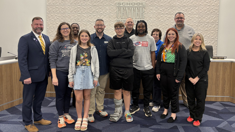 Large group of people stand in front of Center School District sign.