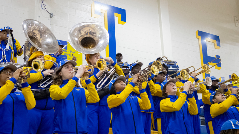 CHS horn section stands in the gym, playing at a basketball game.