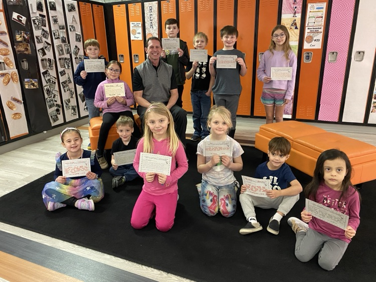 students holding certificates surrounding the principal in front of lockers