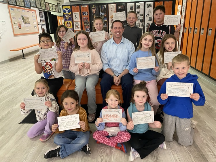 students holding certificates surrounding Principal in front of lockers