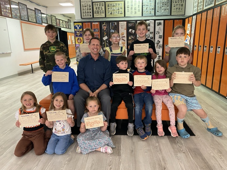 students sitting with the principal holding certificates
