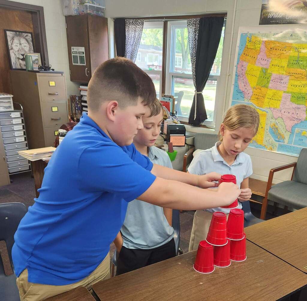 Carefully stacking the cups without using their hands.