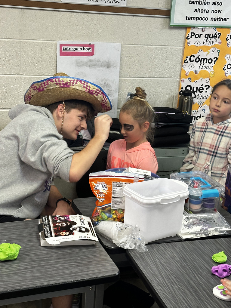 Third grade students getting faces painted like skeletons to celebrate Dia de los Muertos