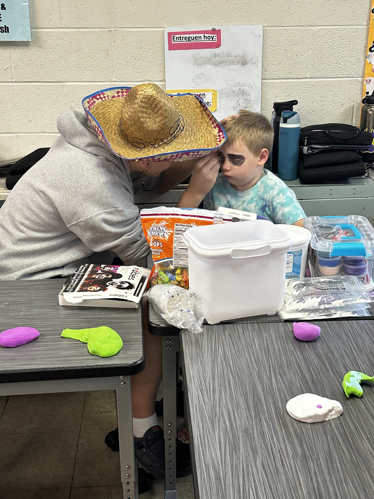 Third grade students getting faces painted like skeletons to celebrate Dia de los Muertos