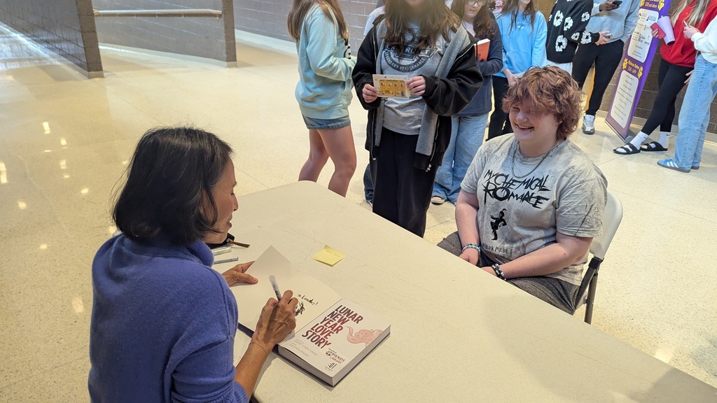 LeUyen Pham signing a book for a student and including a sketch of the student