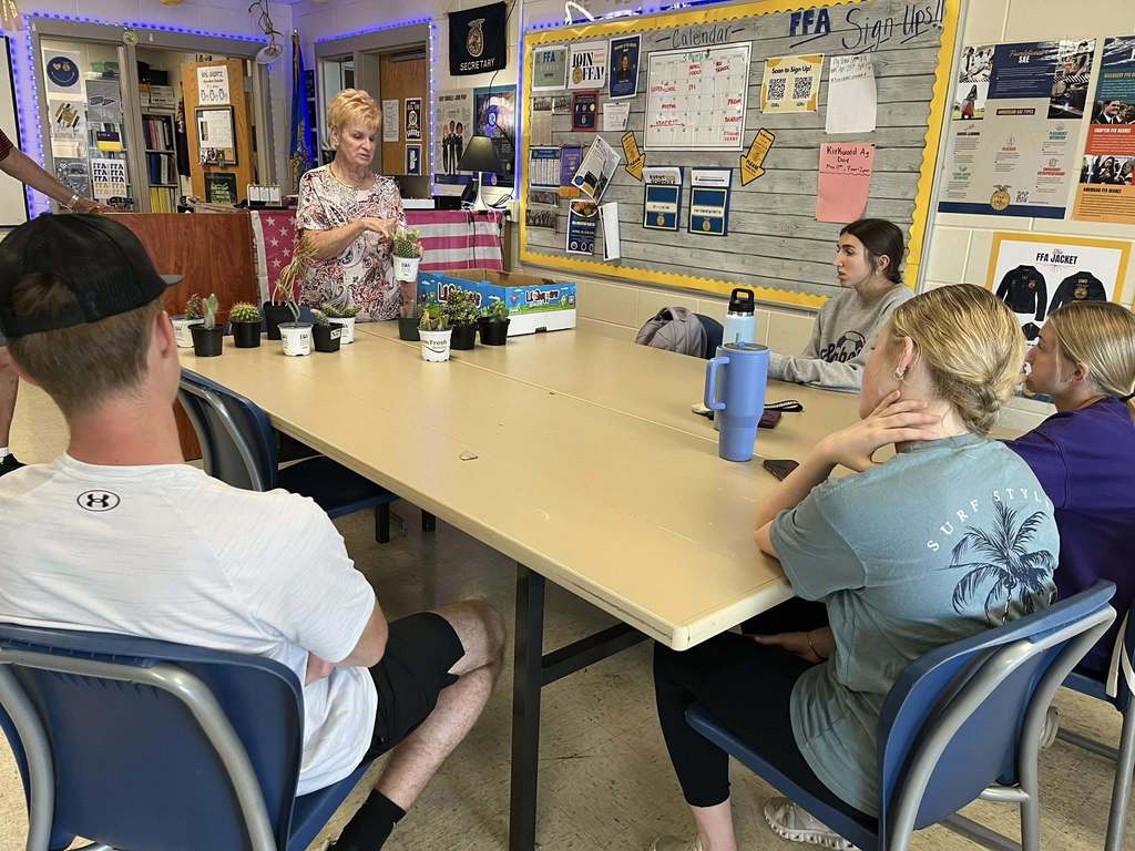 Horticulture students listening to a member of the DeWitt Town and Country Club talk about creating hanging baskets