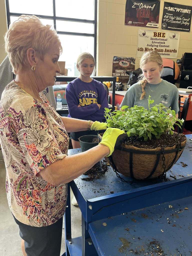 Horticulture students listening to a member of the DeWitt Town and Country Club talk about creating hanging baskets