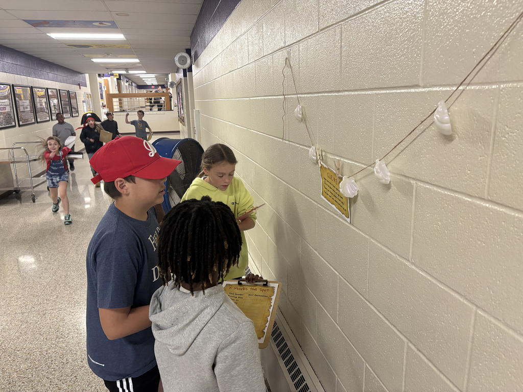 4th graders trying to solve clues that are part of the school-wide treasure hunt