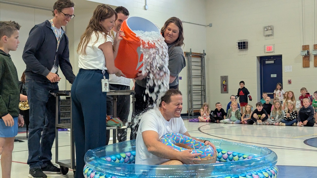 Ms. Wellman and Mrs. Keith dumping a bucket of ice water on Principal Mr. Miller