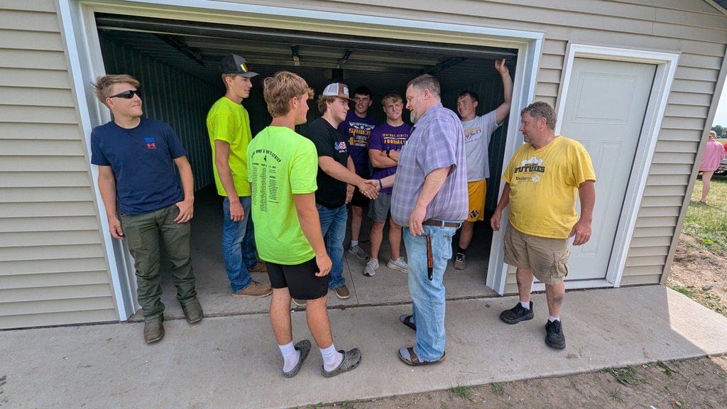 Mr. Greubel shaking the hands of the students who built the shed for the marching band
