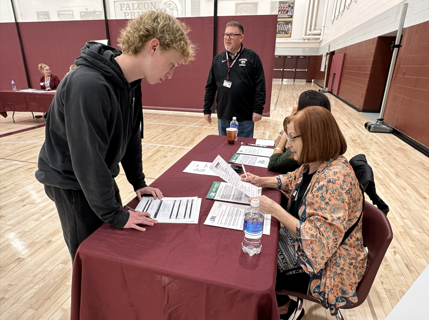 Student at a table with volunteers