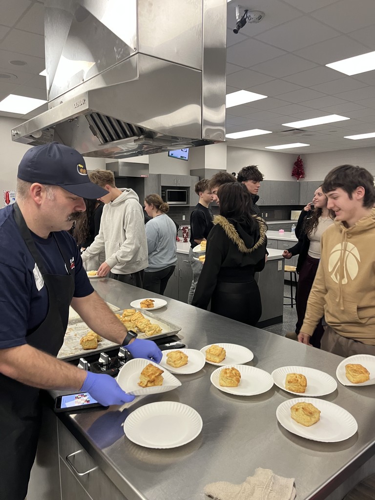 Man serving biscuits to students