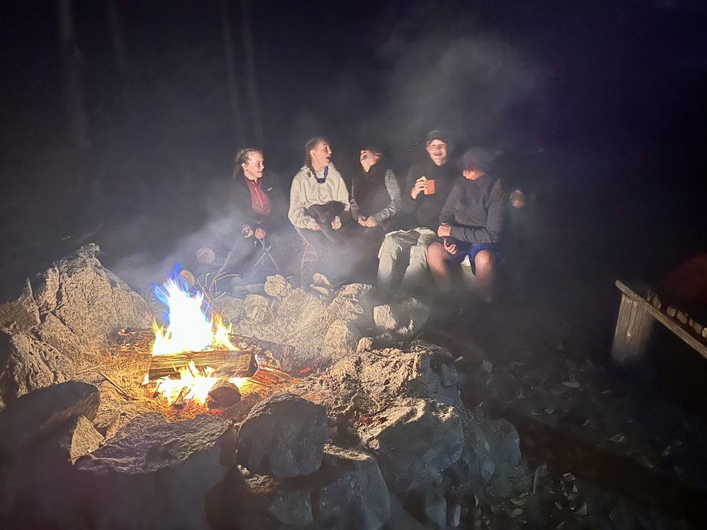 8th grade students laughing around the campfire