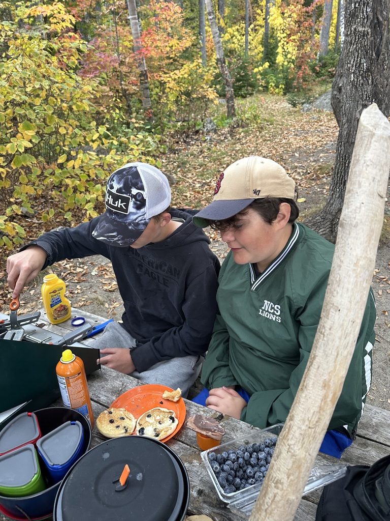 8th grade students making pancakes over a camp stove