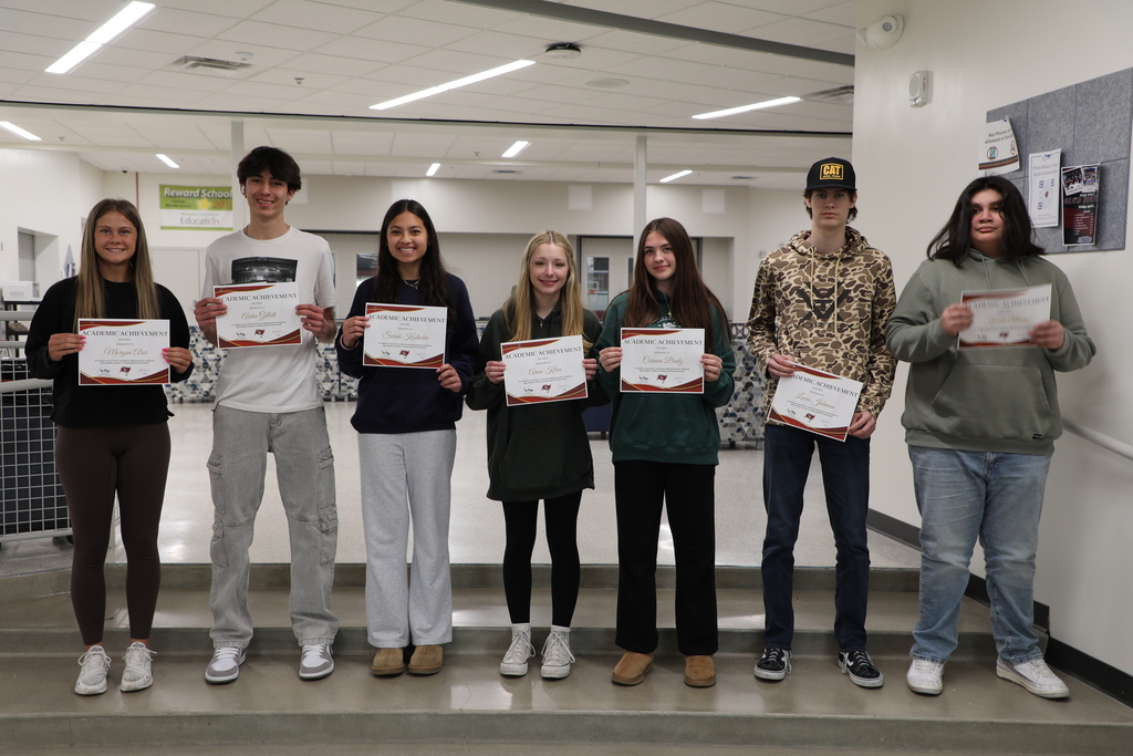 7 students holding awards for their academic achievements. 