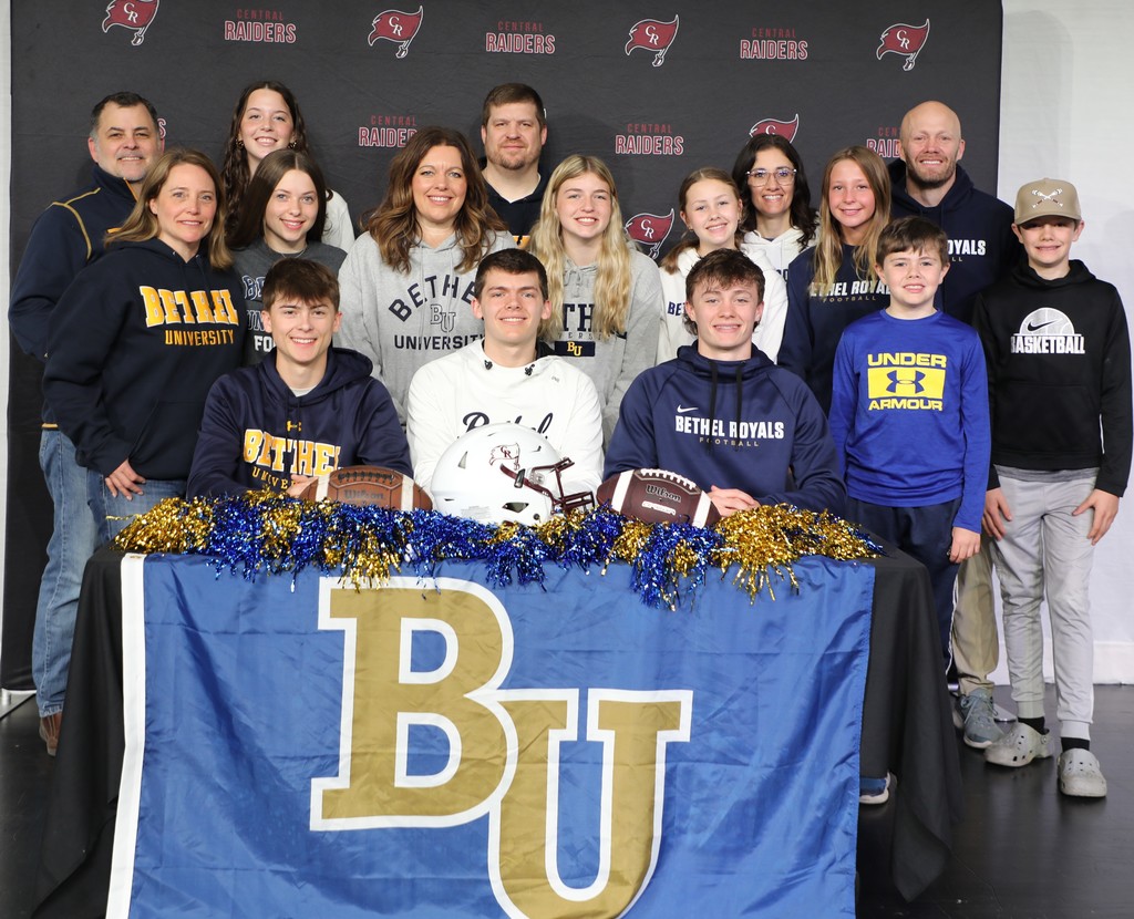 3 high school seniors and their parents celebrating athletic scholarships