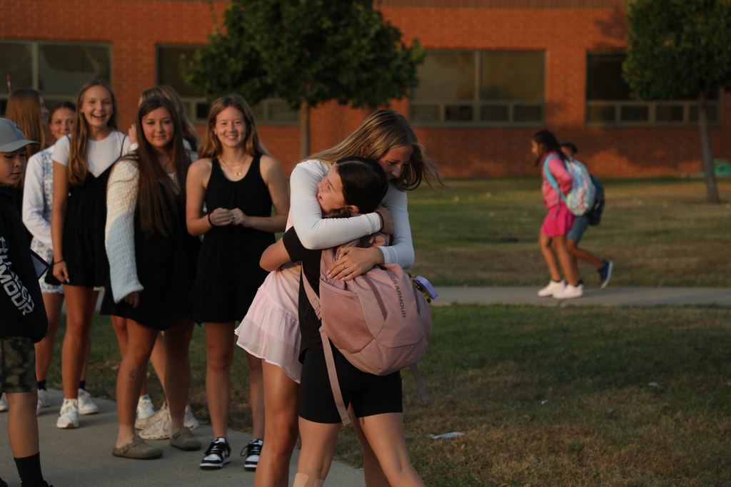 A varsity girls soccer player hugging an elementary student