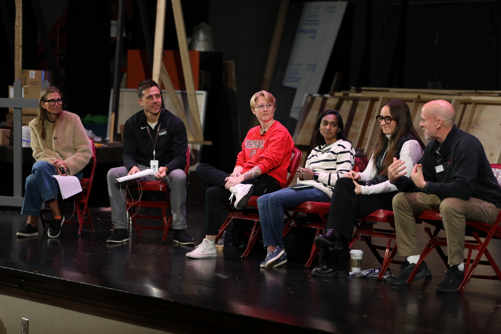 Panel of college reps talk to high school students along with the principal and guidance counselor. 