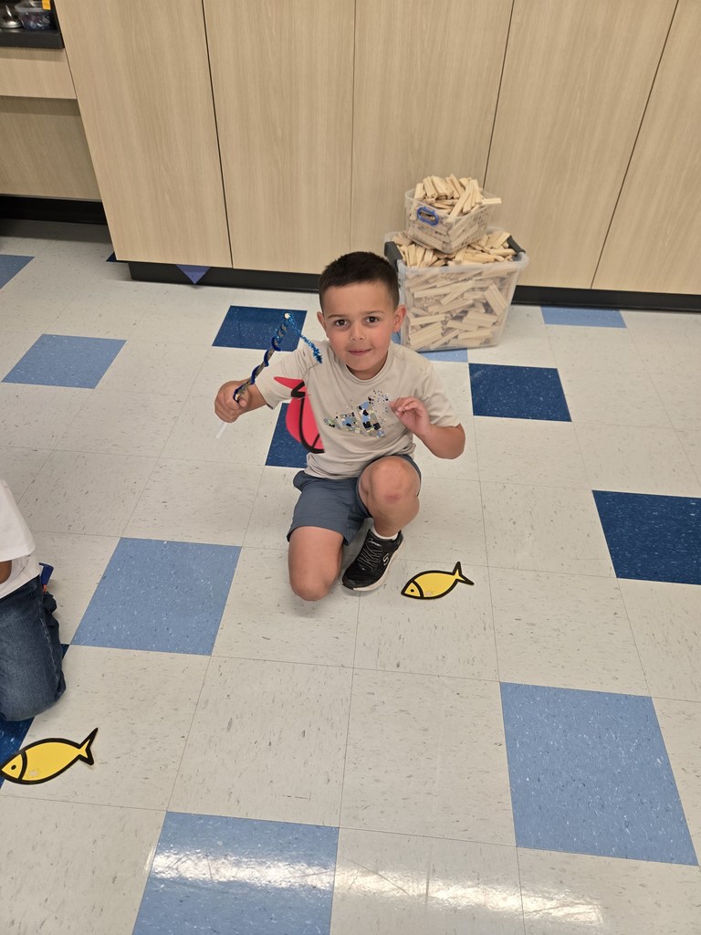 young students using sting and sticks to fish for paper fish