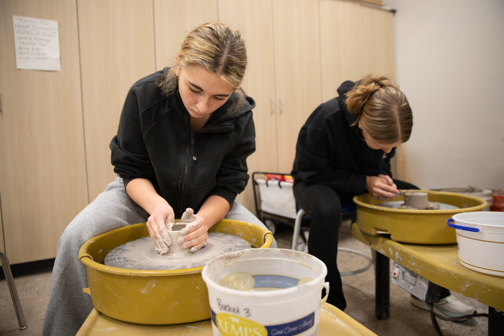 high school students working on pottery