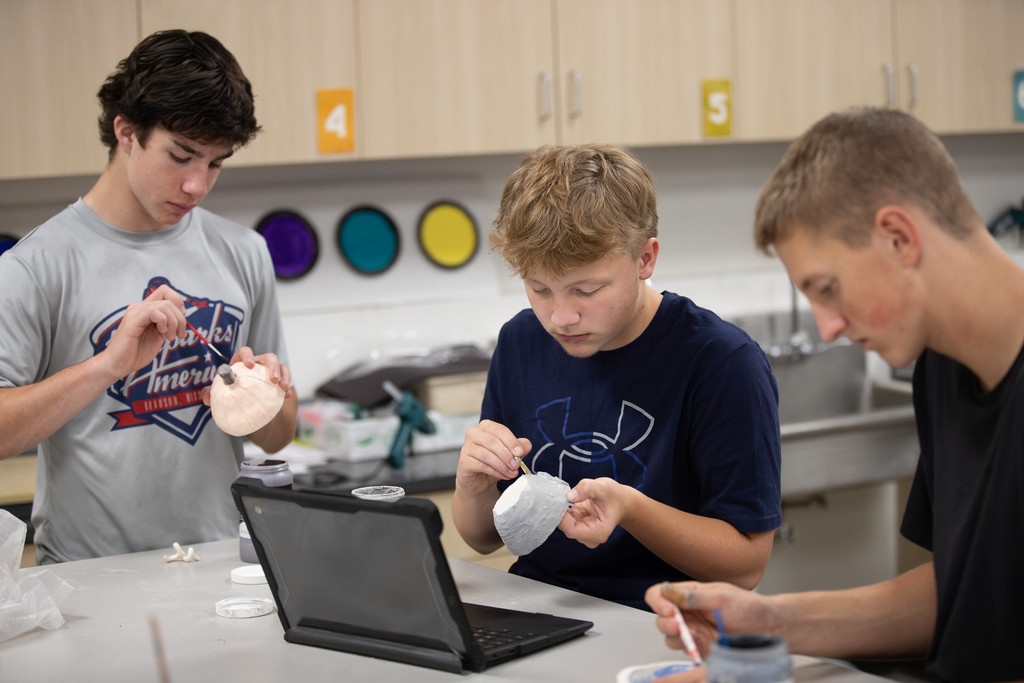 high school students working on pottery