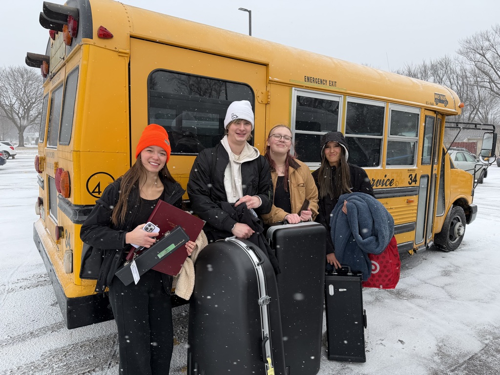 4 high school students standing outside in the snow, before boarding a bus to go to a band competition. 