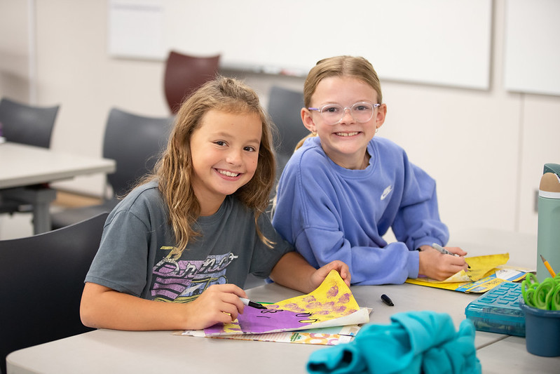 students smiling at the camera while working on project