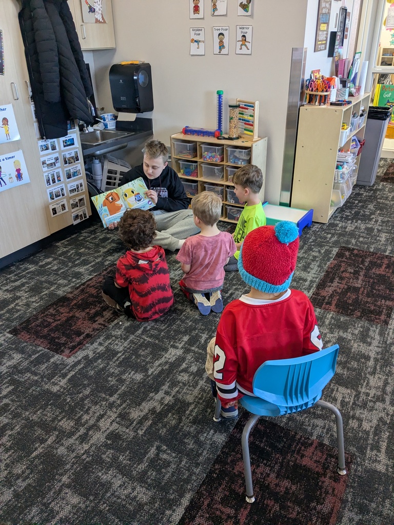 A middle school student reading to preschoolers