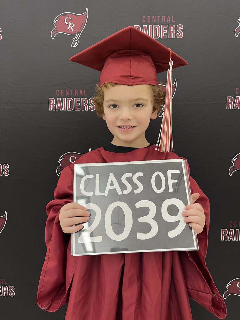 future kindergartener in cap and gown holding sign that says class of 2039