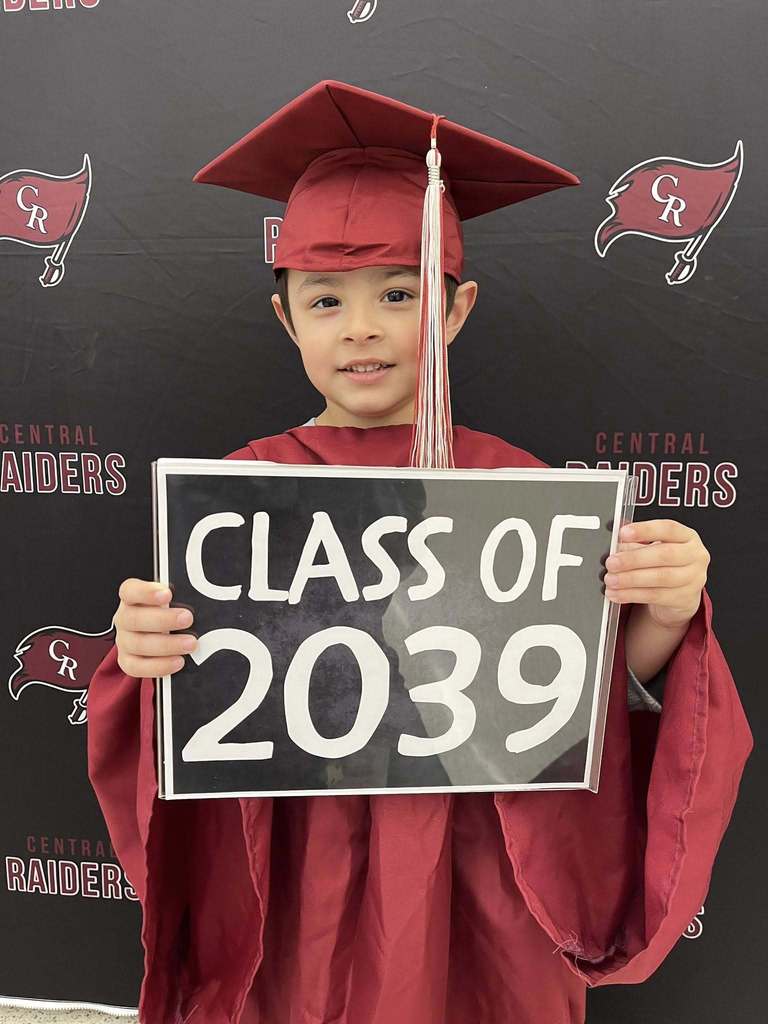 future kindergartener in cap and gown holding sign that says class of 2039