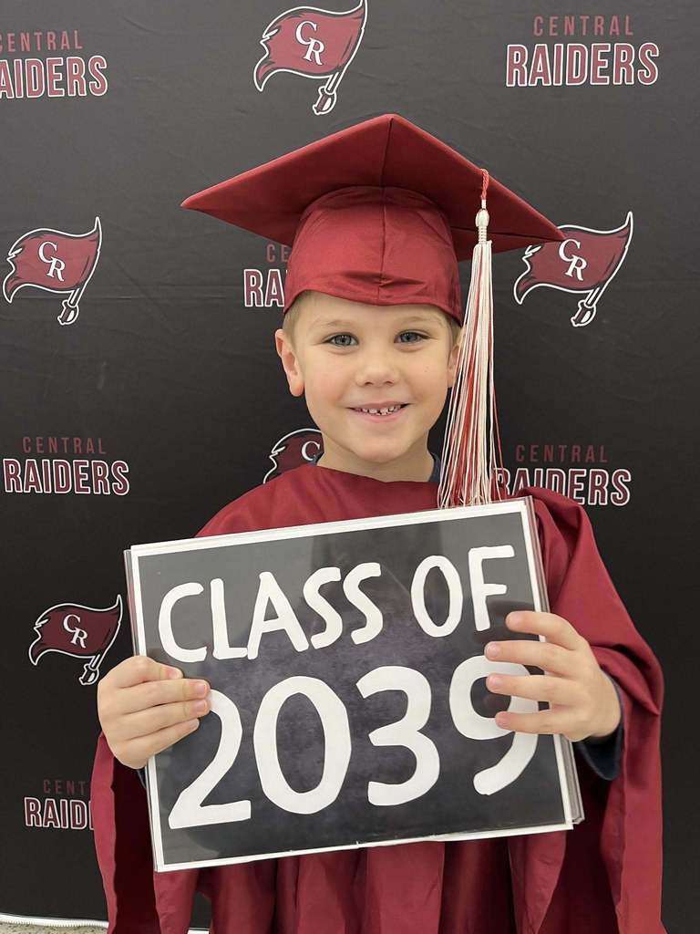future kindergartener in cap and gown holding sign that says class of 2039