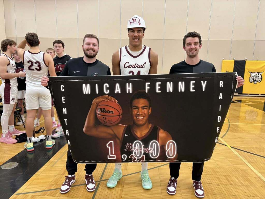 A high school basketball player with his coaches after reaching 1,000 points.