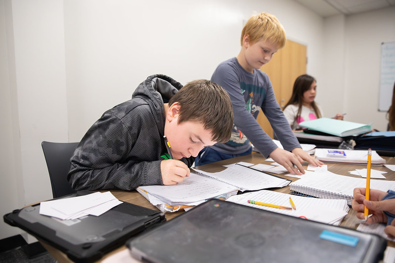 student writing on paper in class