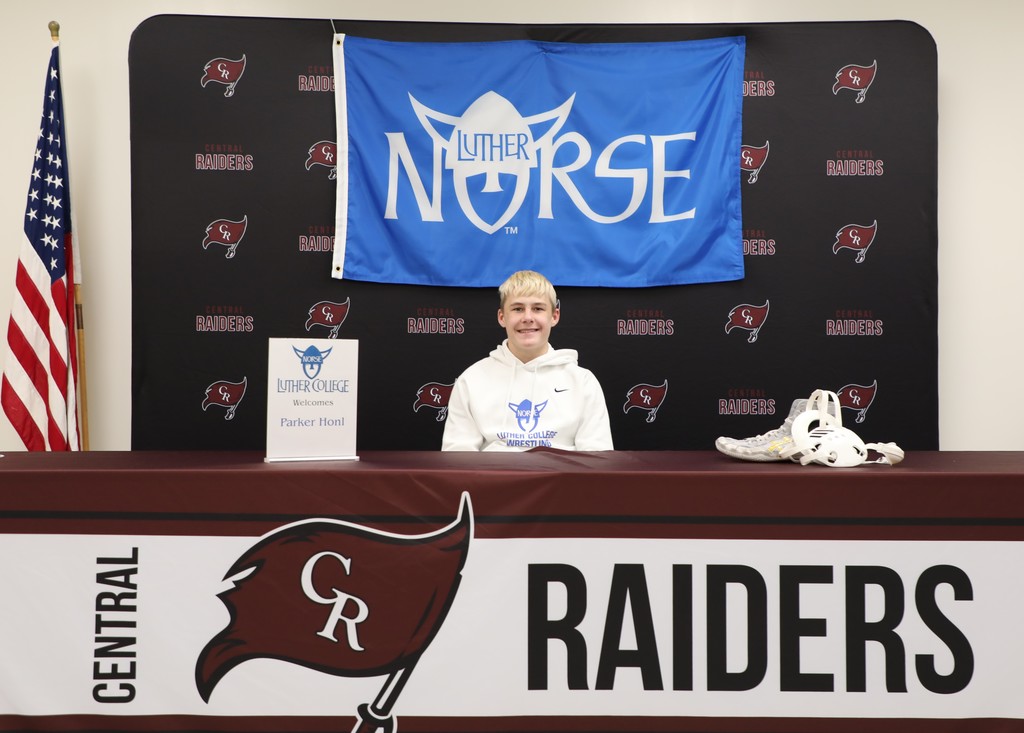 a high school senior smiling after signing to play college wrestling. 