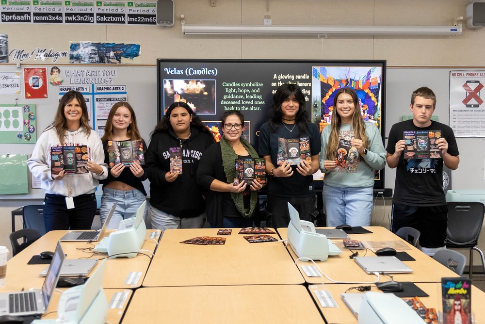 Students with principal, teacher hold brochures they designed