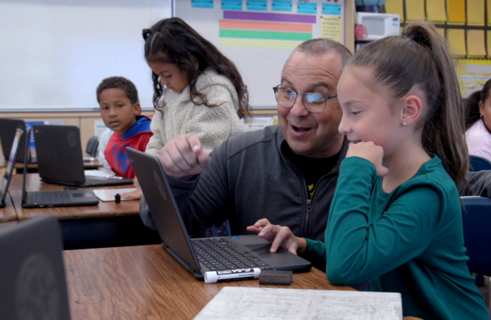 Teacher helping student using Chromebook