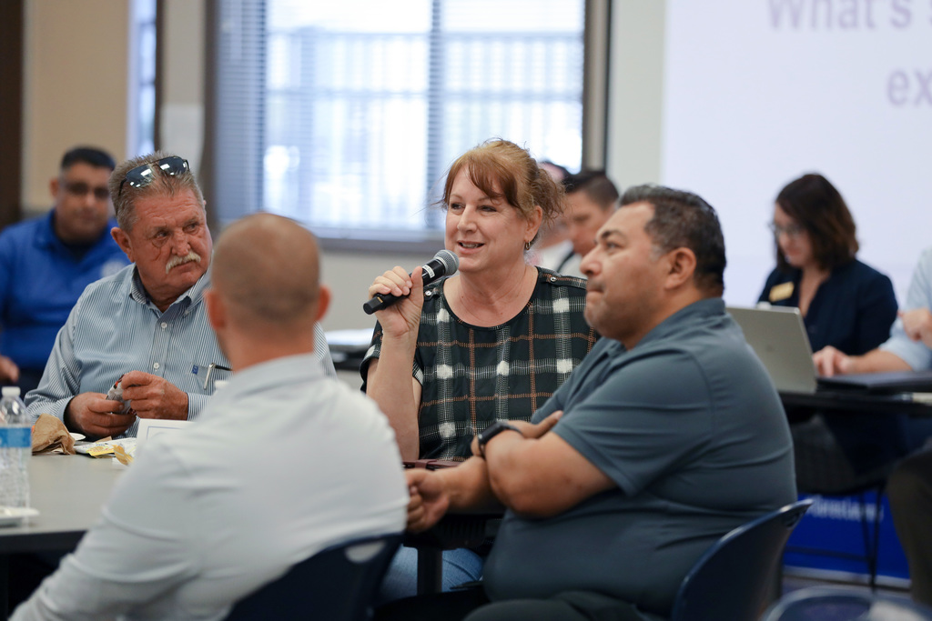 Woman seated with group speaks into microphone