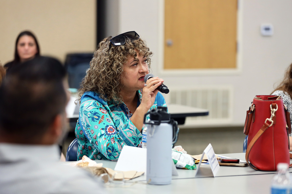Woman seated at table speaks into microphone