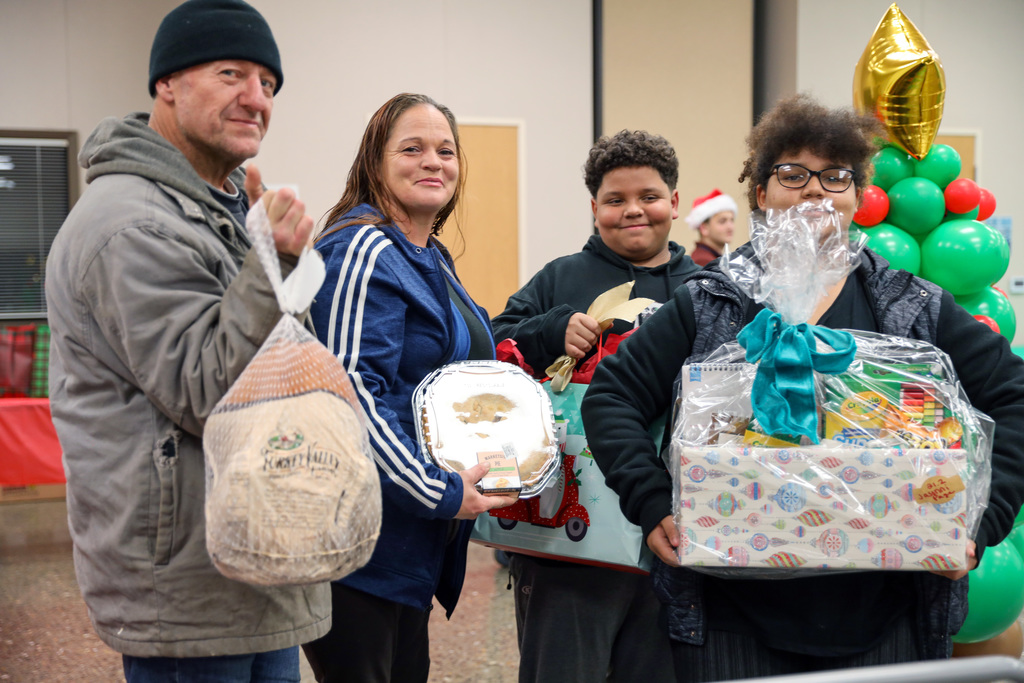 Family holds holiday dinner items including frozen turkey and pie