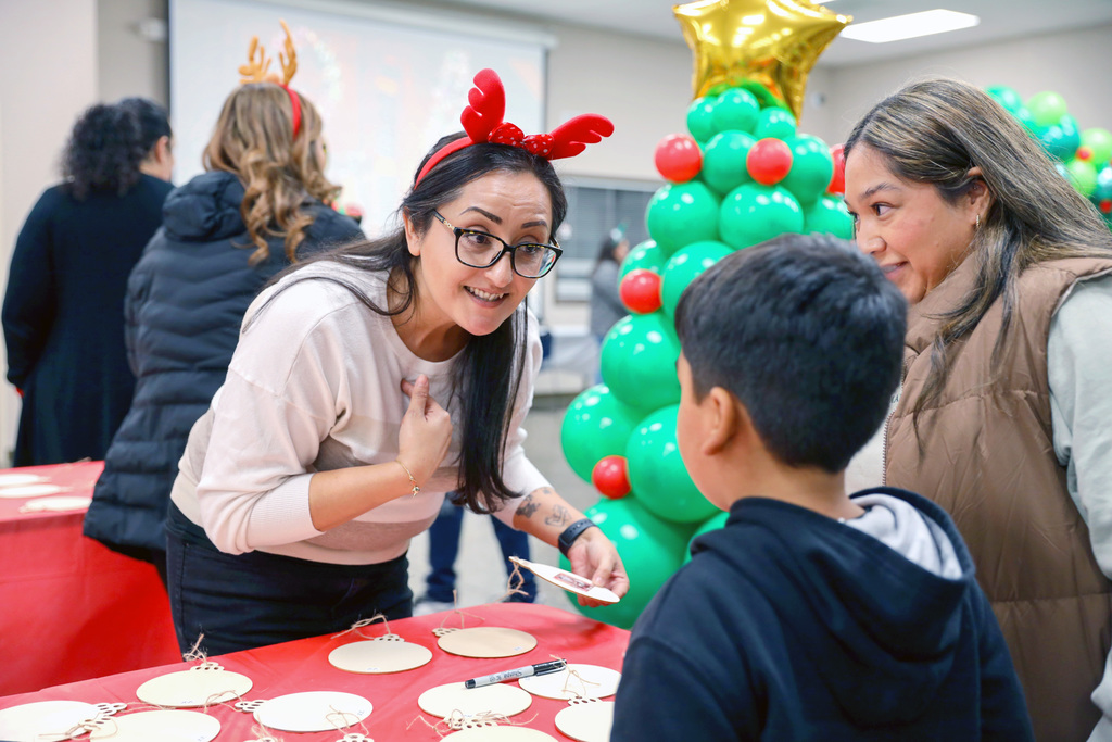 Woman in red antler headband talks with student