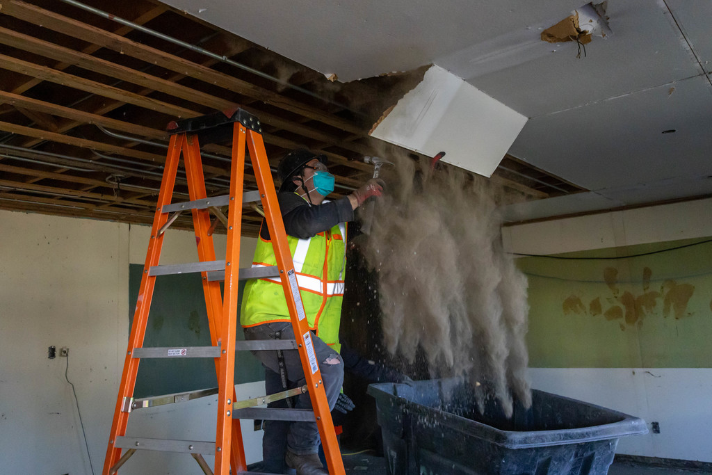 Construction worker removing ceiling panels